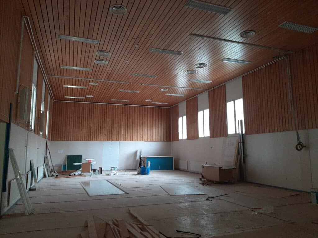 Kuvassa valokuva koulurakennuksen liikuntasalin sisältä, jossa purkutyöt osin aloitettu.