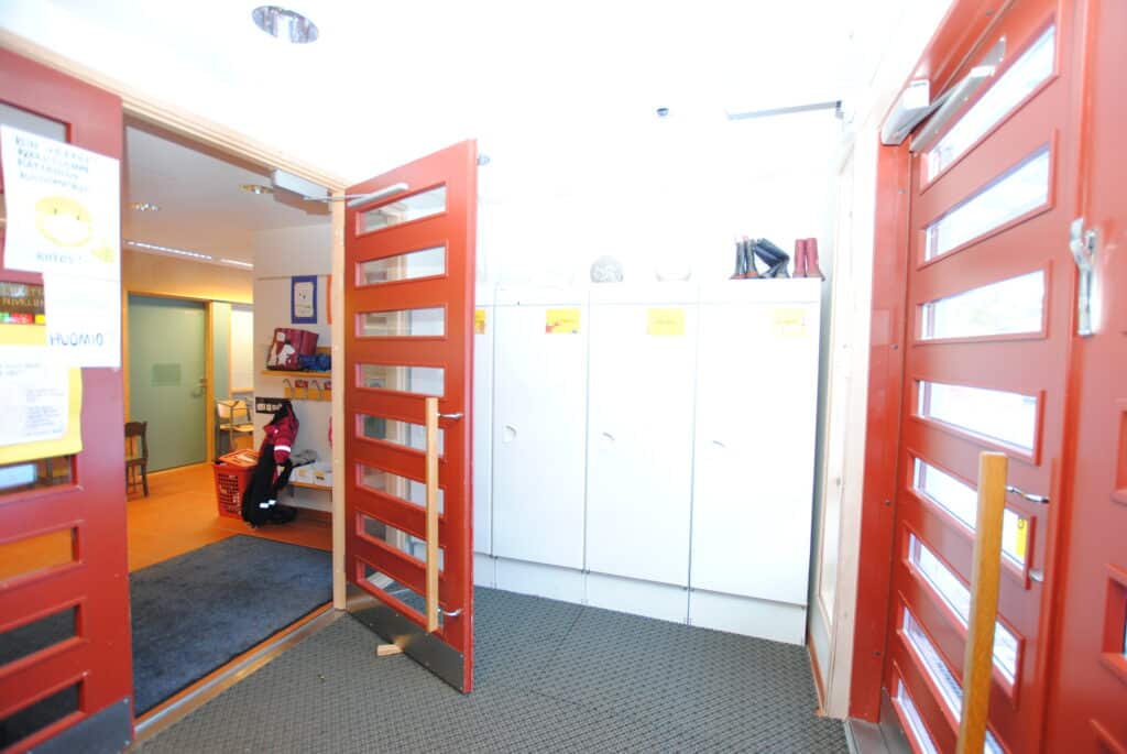 Kuva koulurakennuksen tuulikaapista, jossa on punaisia väliovia.