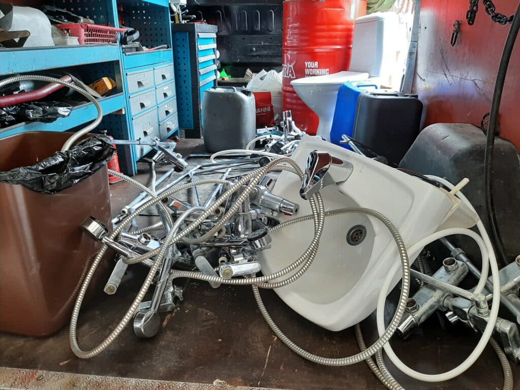 Suihkun sekoittajia, vessanpönttö ja käsienpesuallas pakettiauton kyydissä.