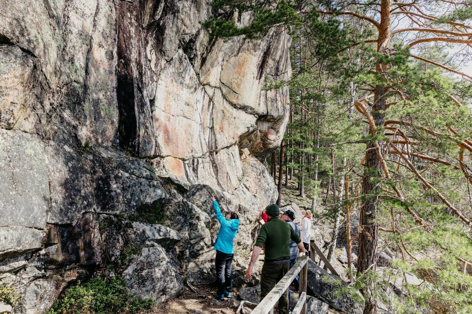 pieni joukko ihmisiä seisoo kallioseinämän edessä