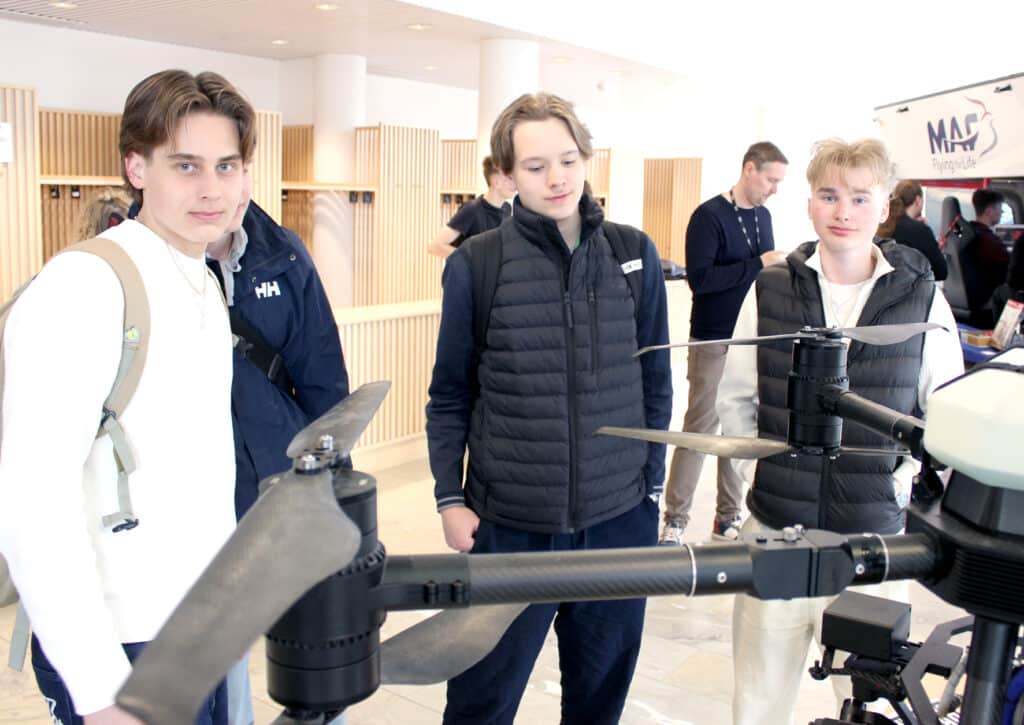 Neljä nuorta seisovat tutkimassa isoa lennokkia.