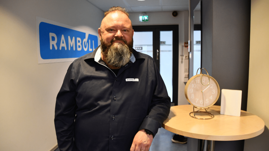 Parrakas mies nojaa puupöytään