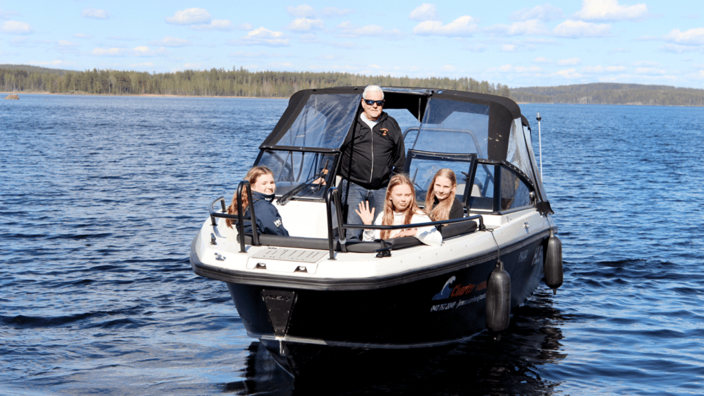 Keskellä järveä isossa mustassa moottoriveneessa ihmisiä